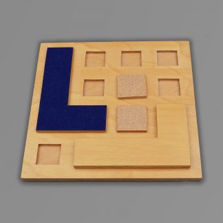 Billede af "L-spillet". Firkantet træplade med kvadratiske huller og to L formede brikker samt to firkantede brikker, der passer i hullerne.
